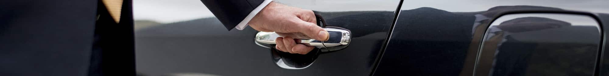 Close-up of a chauffeur's hand opening a car door for a client